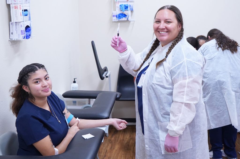 Students practice blood draws during their training to become a phlebotomist in California.