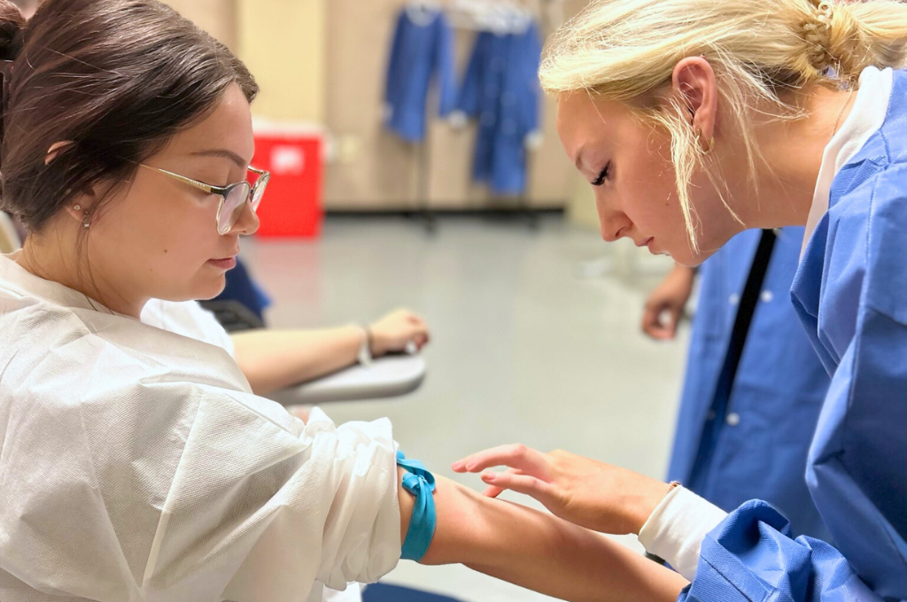 Phlebotomy technician learning how to find vein for blood draw.