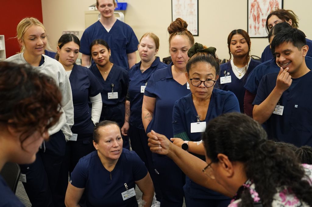 A group of future Certified Medical Assistants listen to instructor in class.