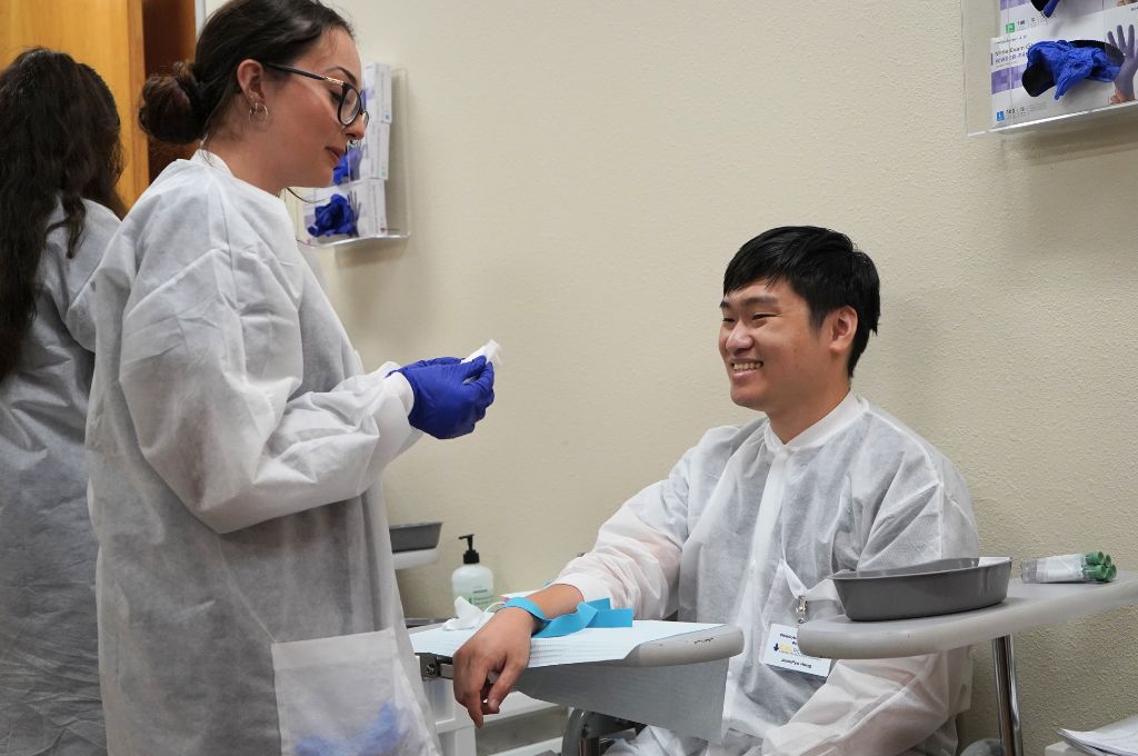 A phlebotomy tech prepares a volunteer for venipuncture. 