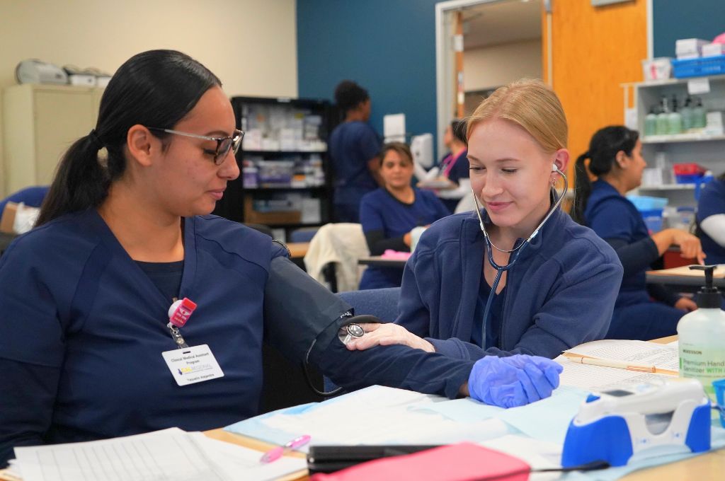 A patient care technician student practices taking vitals.