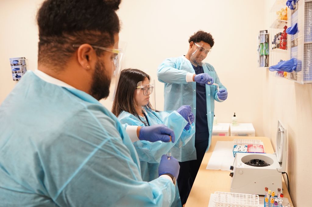 Phlebotomy students preparing blood specimen tubes before centrifuge processing during lab training