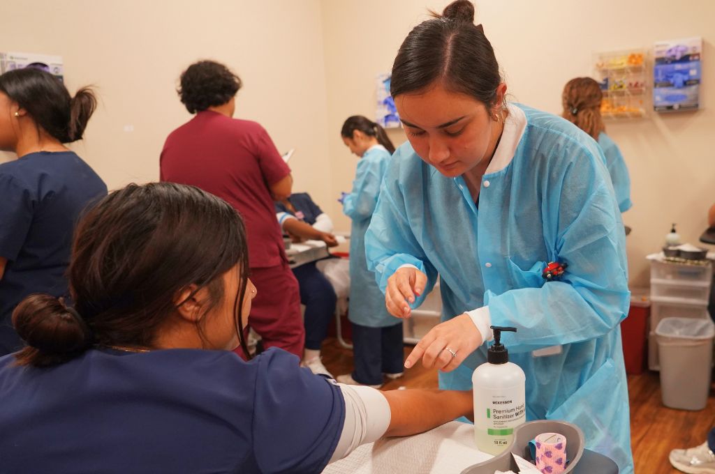 Phlebotomy student sanitizing hands before hands-on blood draw practice