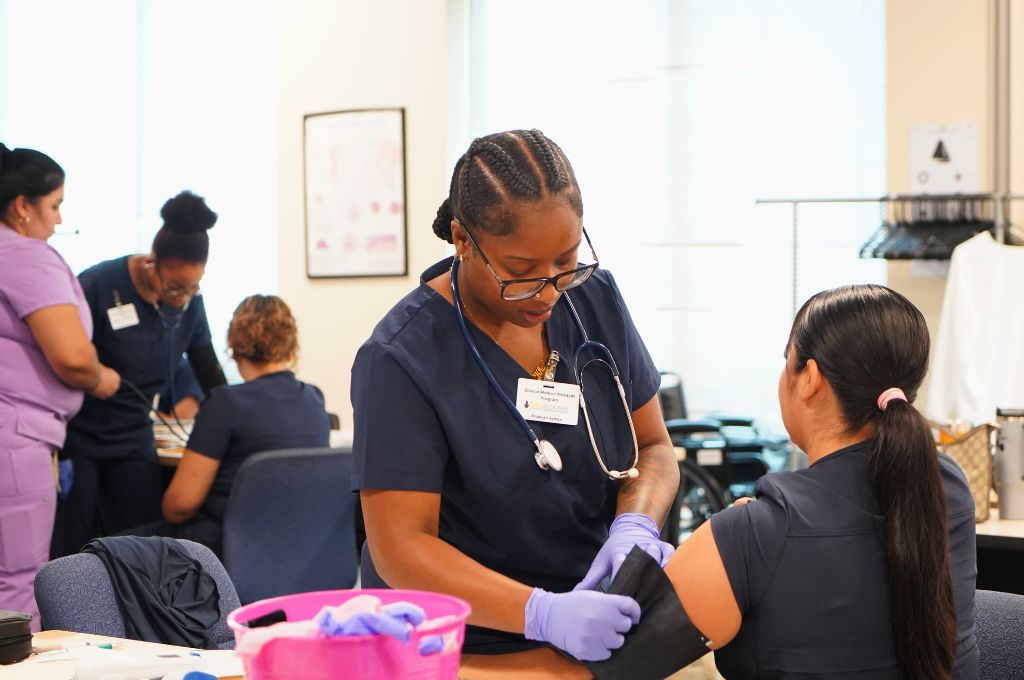 Medical assistant student practicing blood pressure reading on a classmate