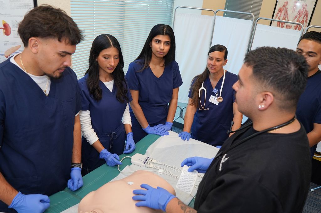 CALRegional students practicing EKG lead placement on a training mannequin during clinical training